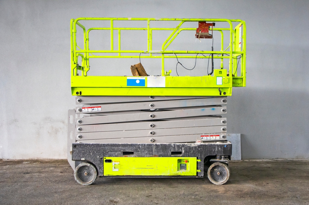 Scissor lift, a lifting machine with a hydraulic system in operation, stands near the construction site