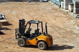 Yellow Forklift on a Construction Site with Sandy Ground and Building Materials