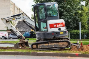Mini excavator and skid steer clearing soil in a residential backyard with Sage Equipment Rentals