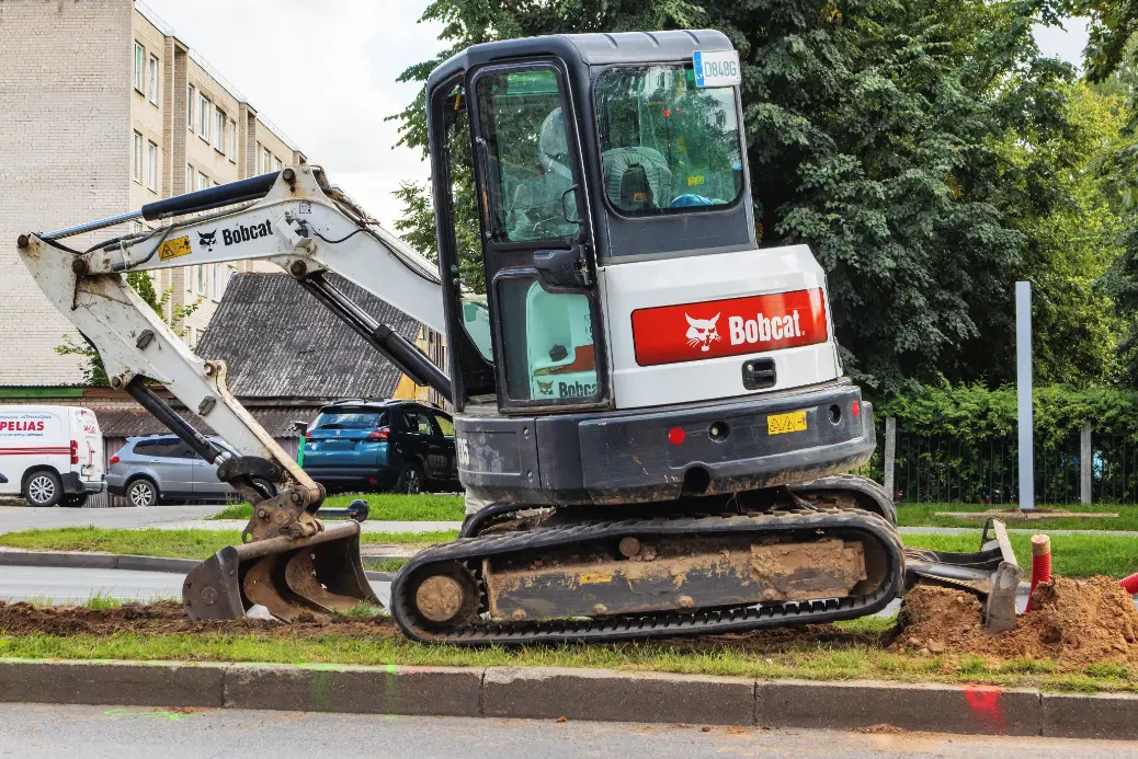 Mini excavator and skid steer clearing soil in a residential backyard with Sage Equipment Rentals